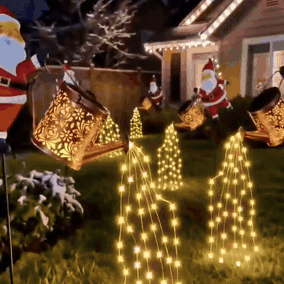 Papá Noel con regadera de luces en el jardín